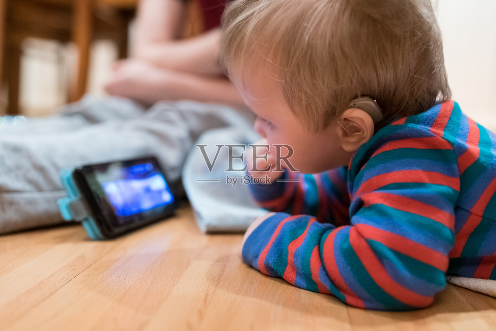 半聋婴儿在智能手机上看和听摇篮曲照片摄影图片