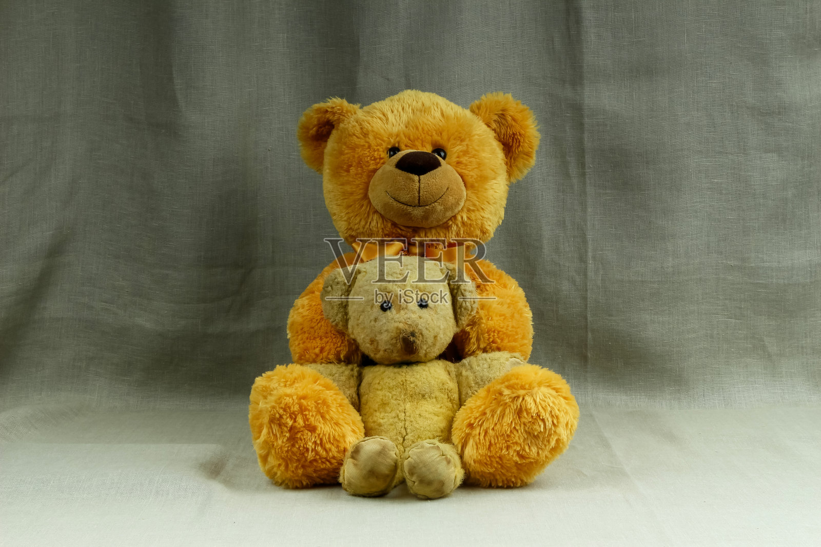 大大的橙色微笑着，还有一个小小的老式黄色泰迪熊照片摄影图片