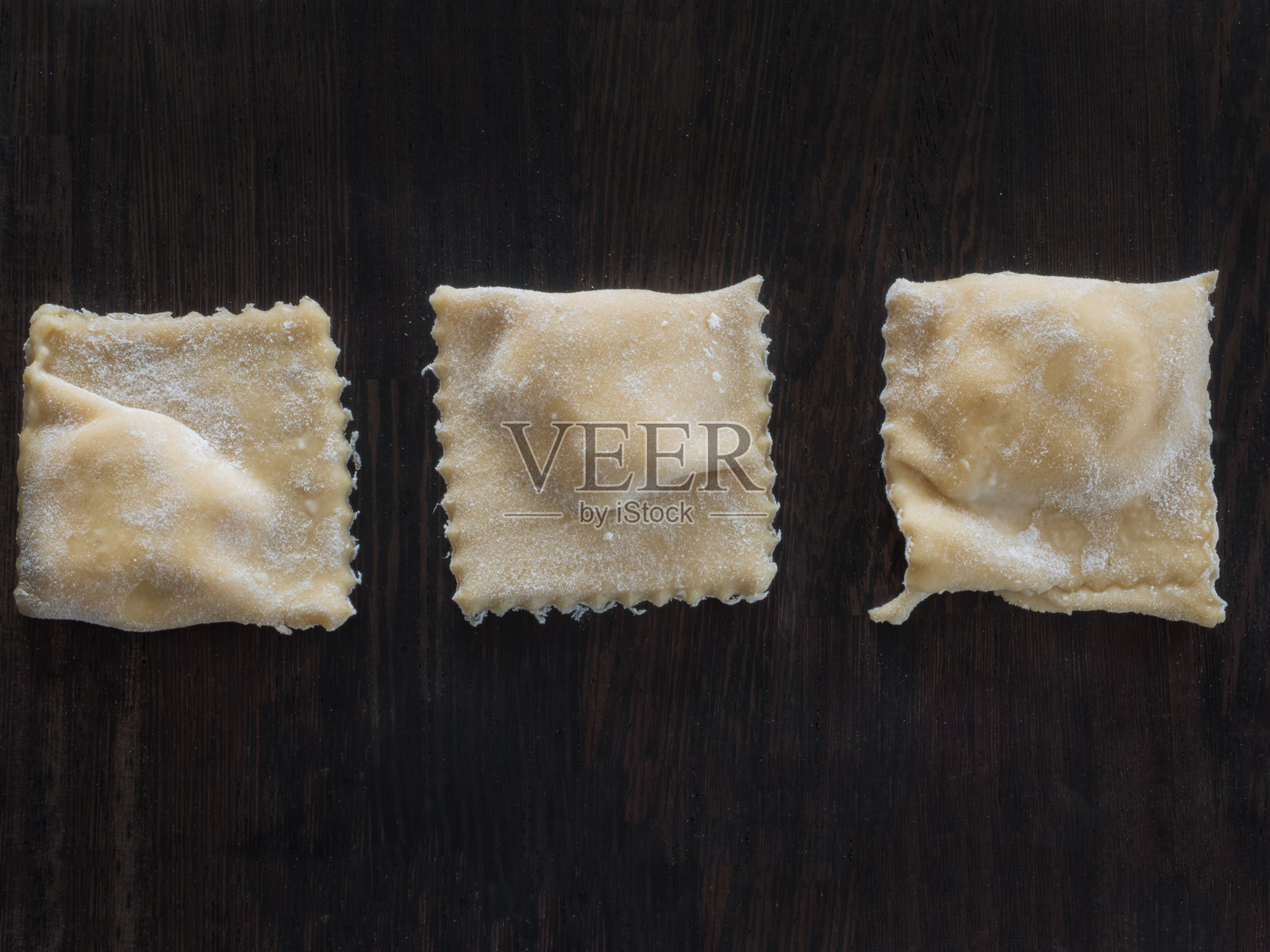 木板上放上面粉的新鲜馄饨照片摄影图片