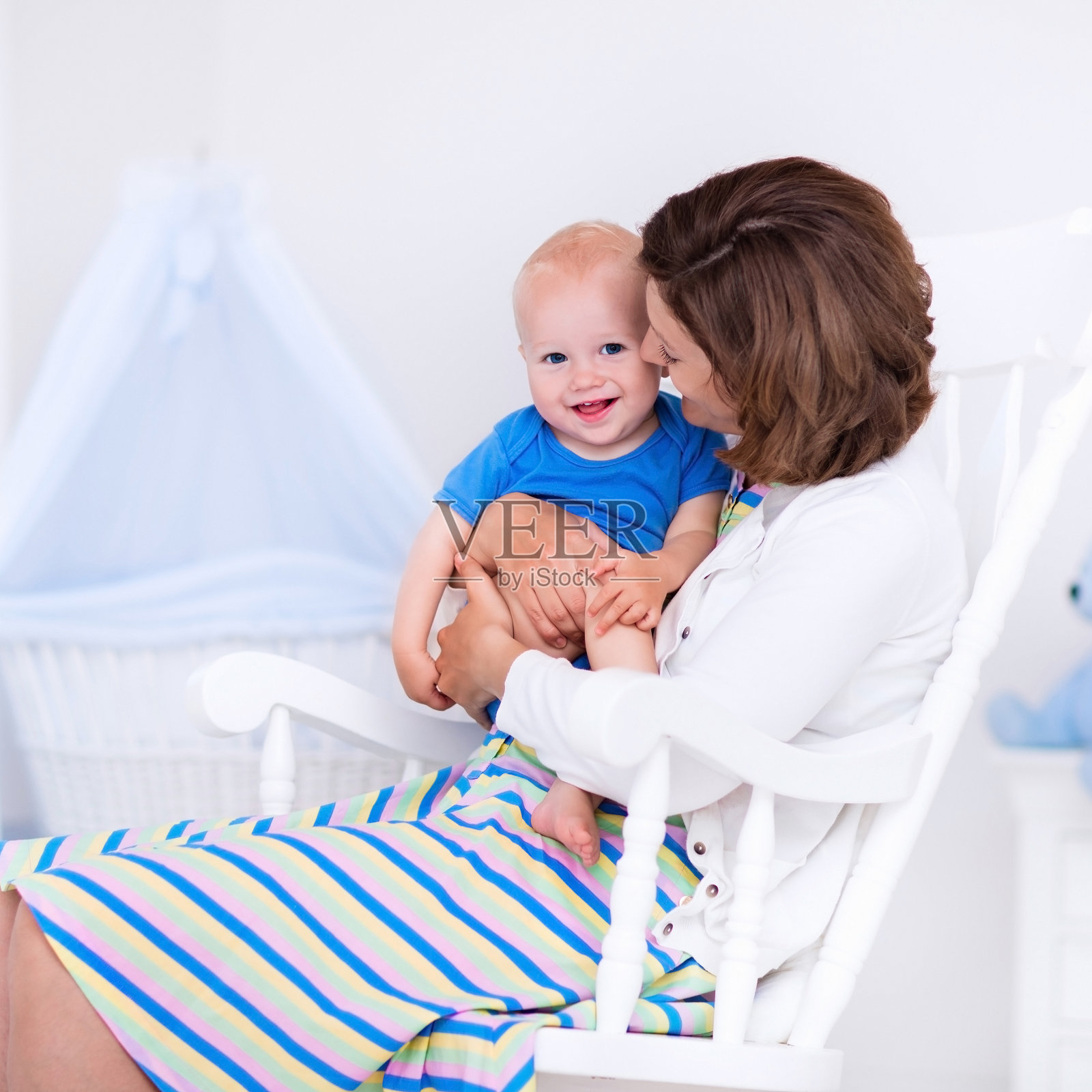 年轻的母亲和婴儿在白色的卧室里照片摄影图片