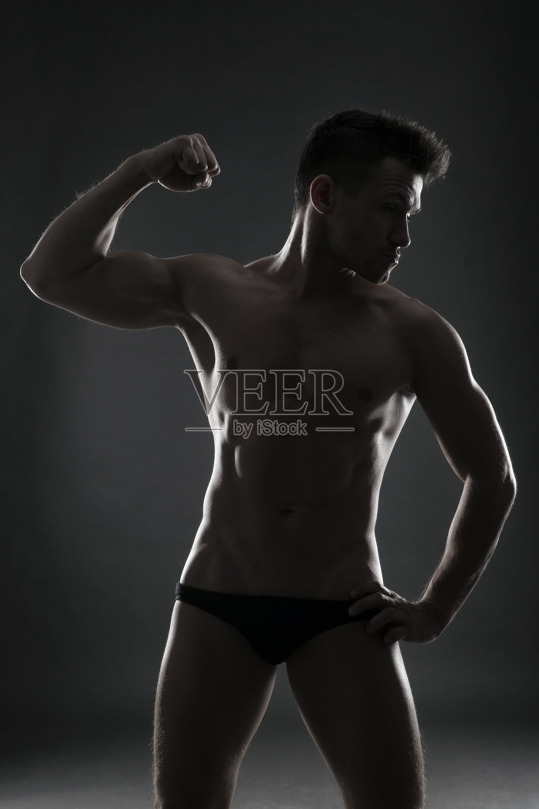 英俊的肌肉健美者在灰色背景摆姿势照片摄影图片