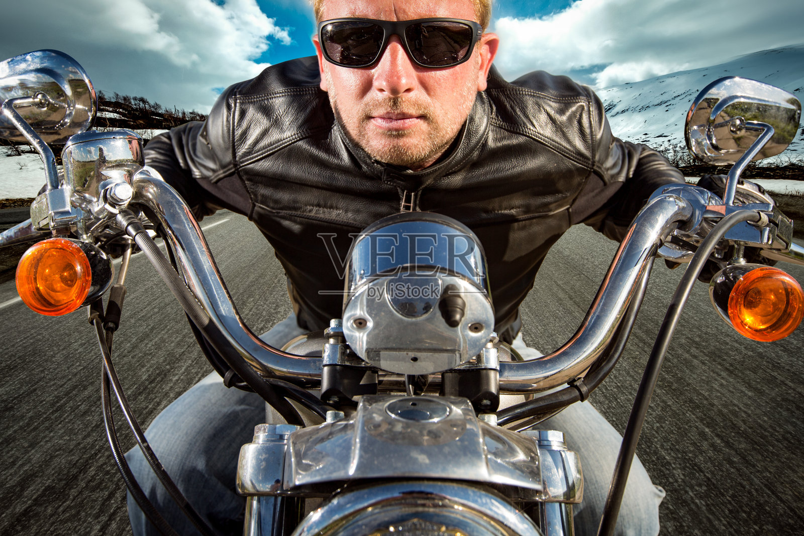 滑稽的摩托车手戴着太阳镜和皮夹克在山上赛跑照片摄影图片