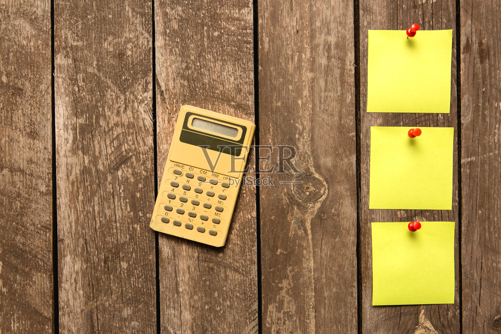 计算器和黄色空白黏贴笔记在木制背景上照片摄影图片