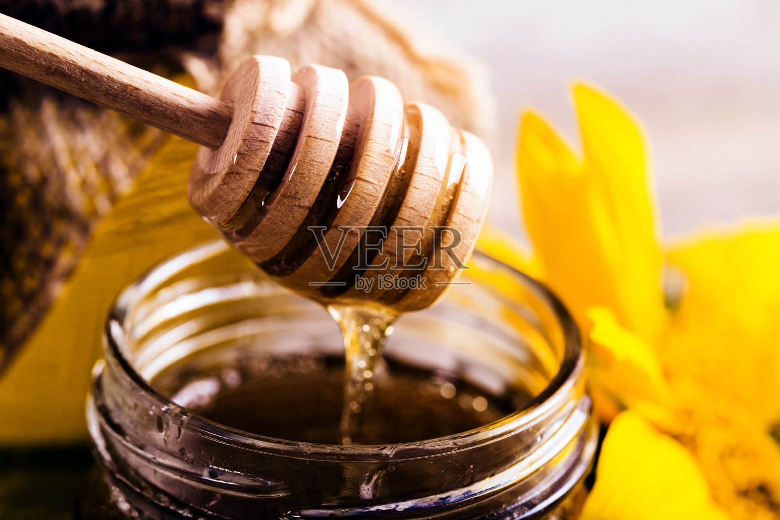 一罐蜂蜜和一勺向日葵照片摄影图片