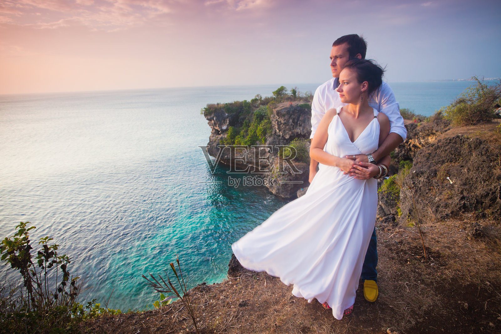 一对旅行情侣穿着白色的衣服在岩石的顶端照片摄影图片