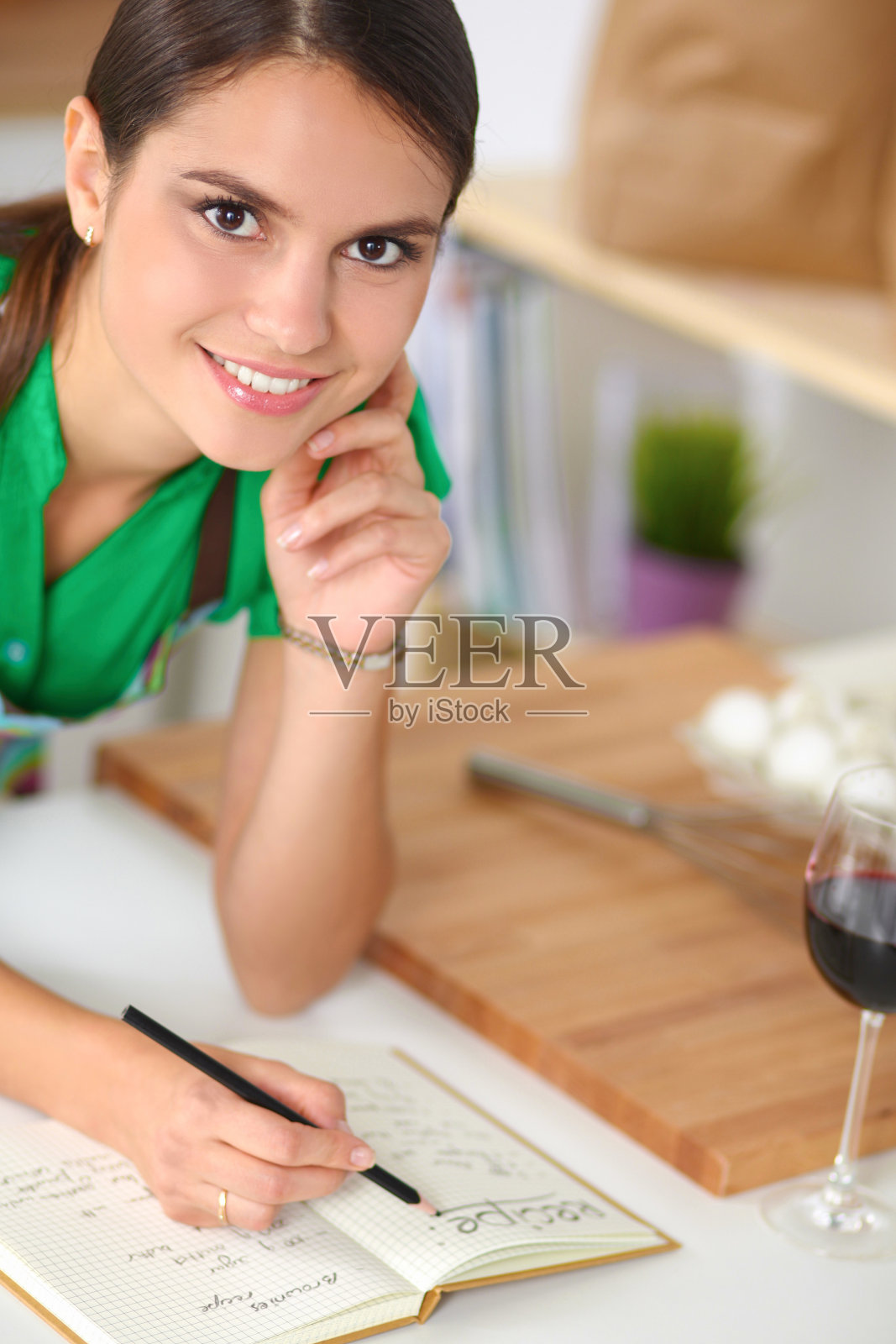 幸福美丽的女人站在厨房里写着照片摄影图片