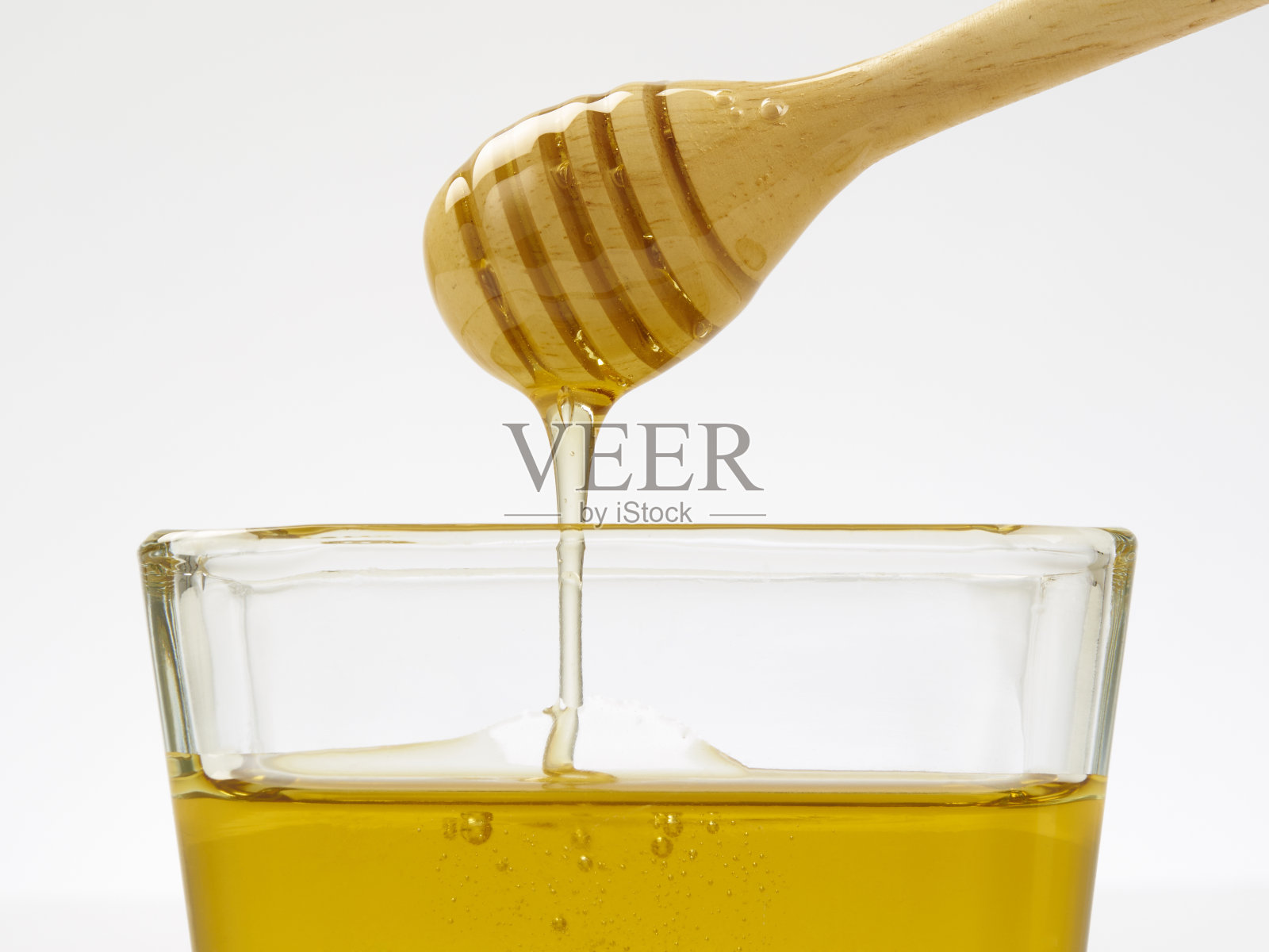 蜂蜜滴与勺子在白色的背景照片摄影图片