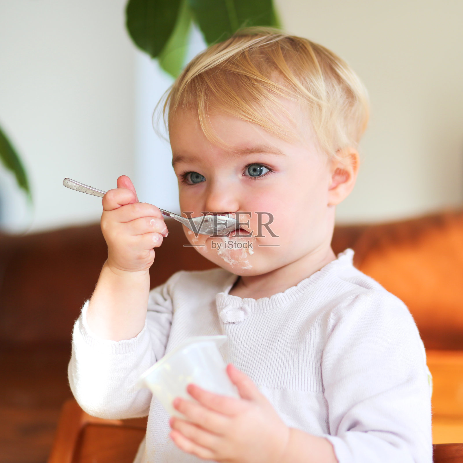 可爱的蹒跚学步的小女孩在吃美味的酸奶照片摄影图片