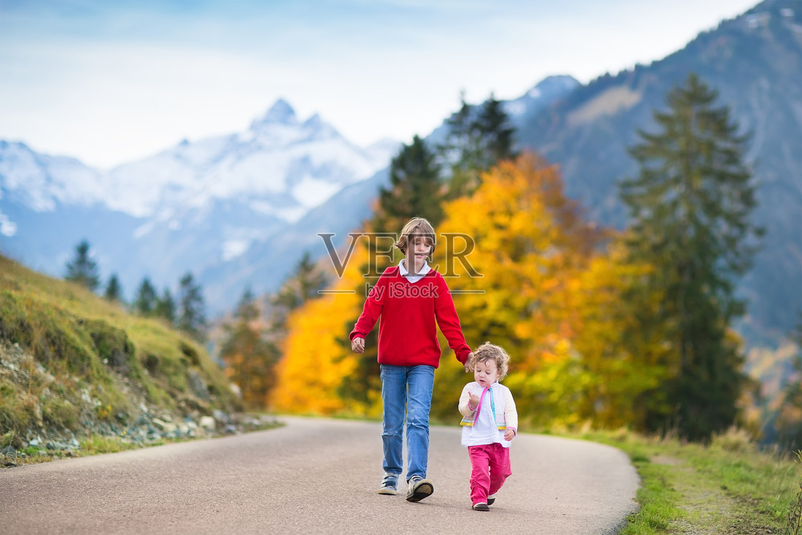 快乐的男孩和他的小妹妹走在山路上照片摄影图片