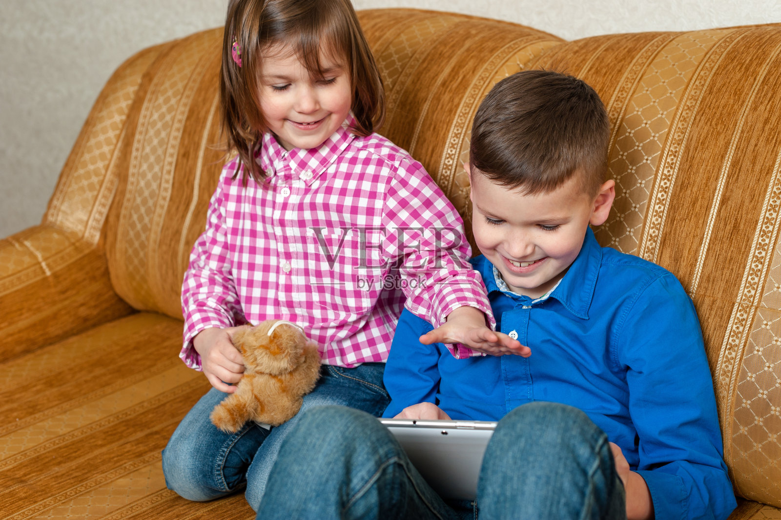 快乐微笑的男孩和女孩与一个数字平板电脑照片摄影图片