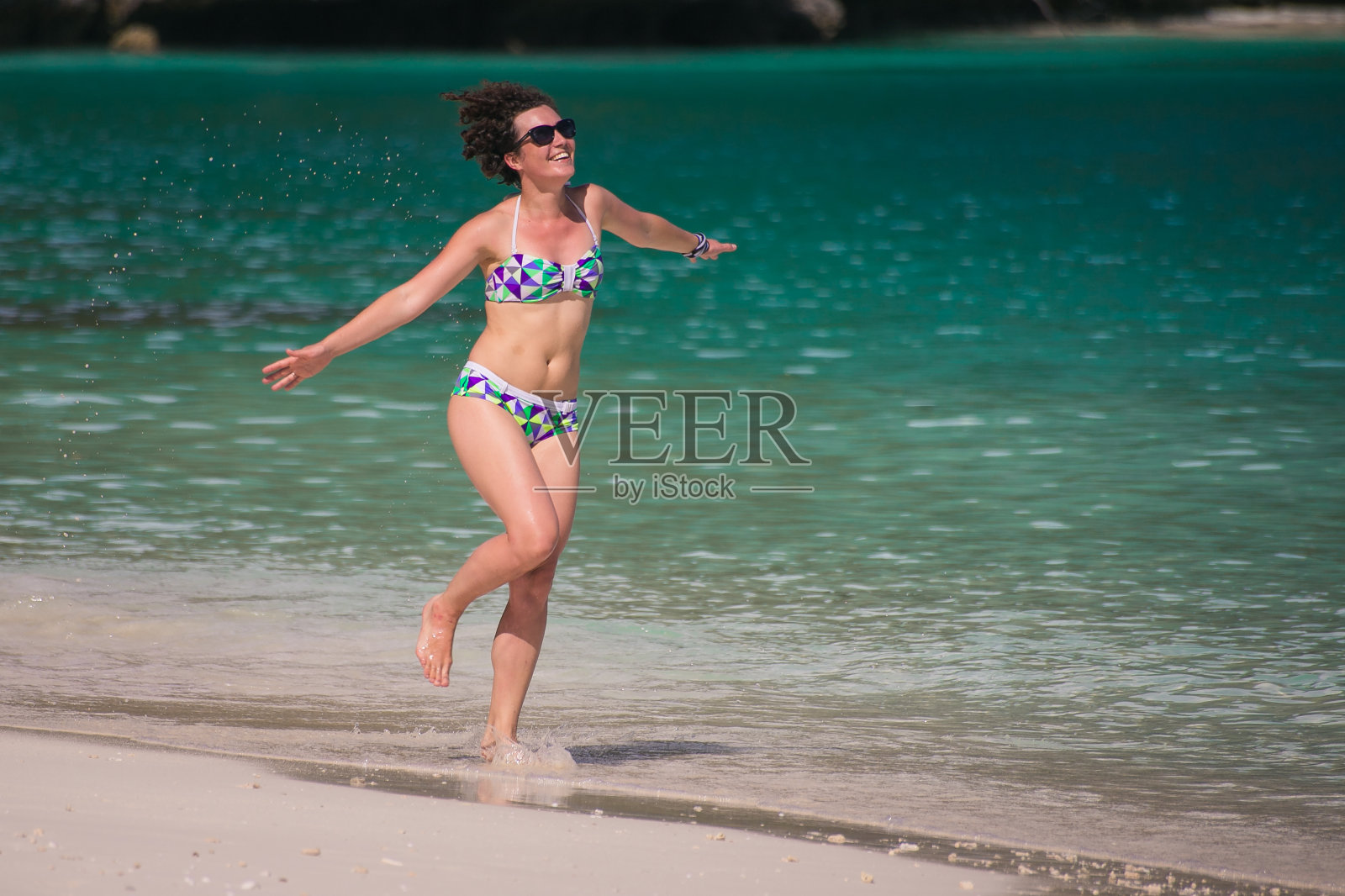 年轻漂亮的女人在沙滩上跑步照片摄影图片