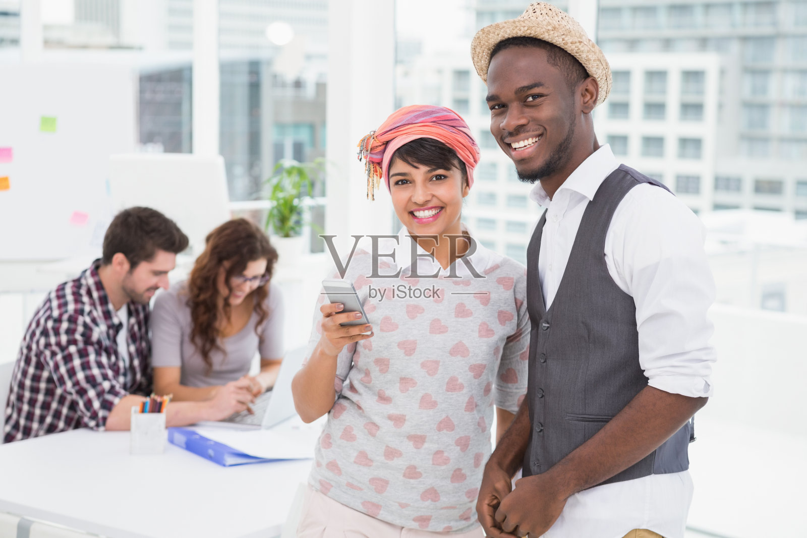 微笑的同事拿着手机站着照片摄影图片