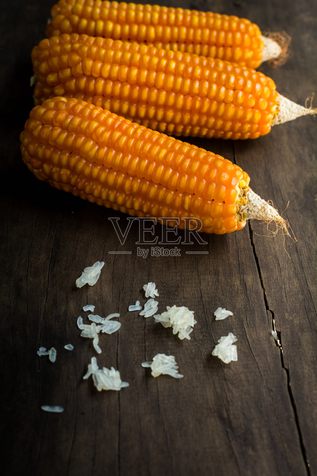 木桌上放着黄色的干玉米。照片摄影图片