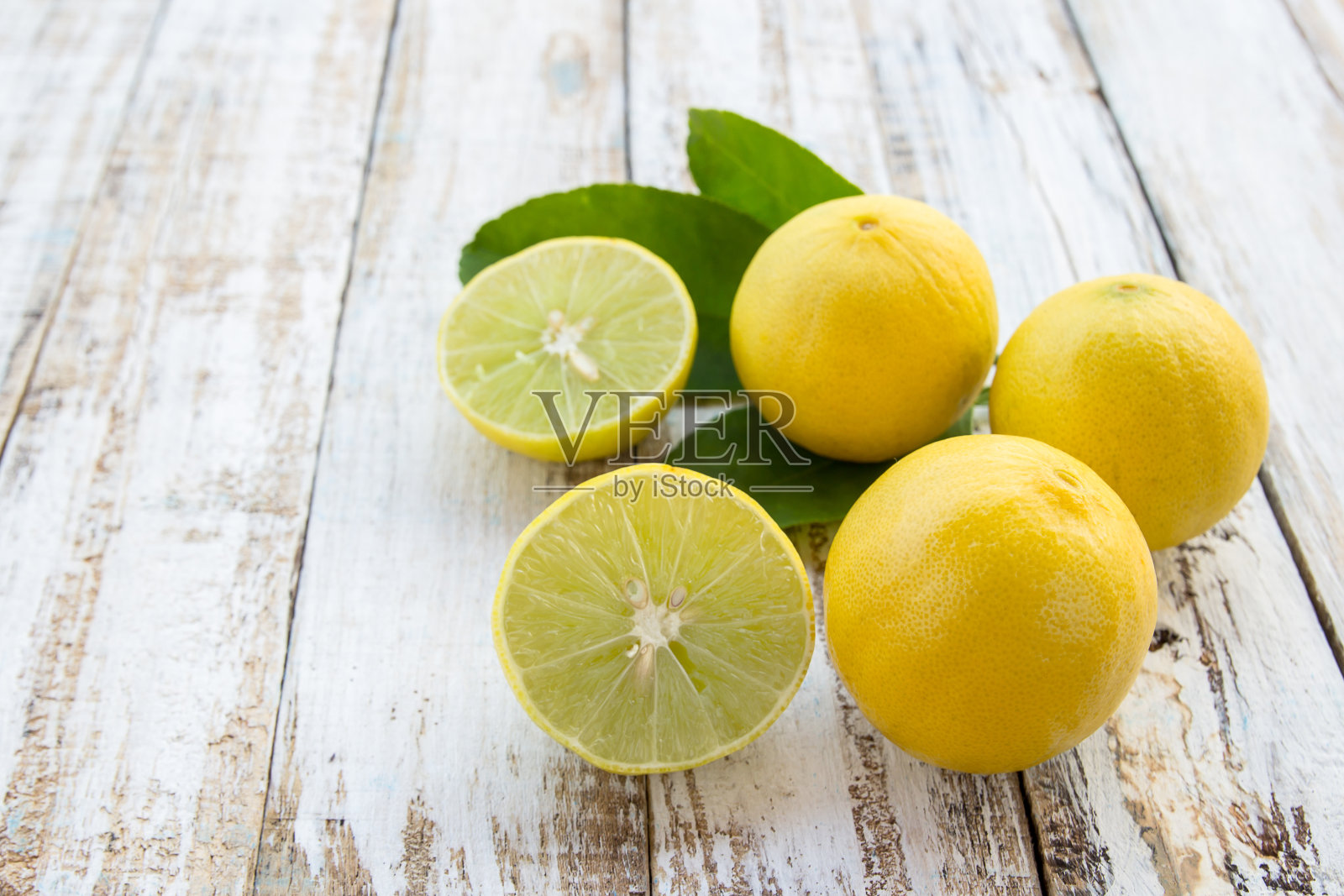 在白色的木桌上，切成两半的新鲜柠檬和整个柠檬照片摄影图片