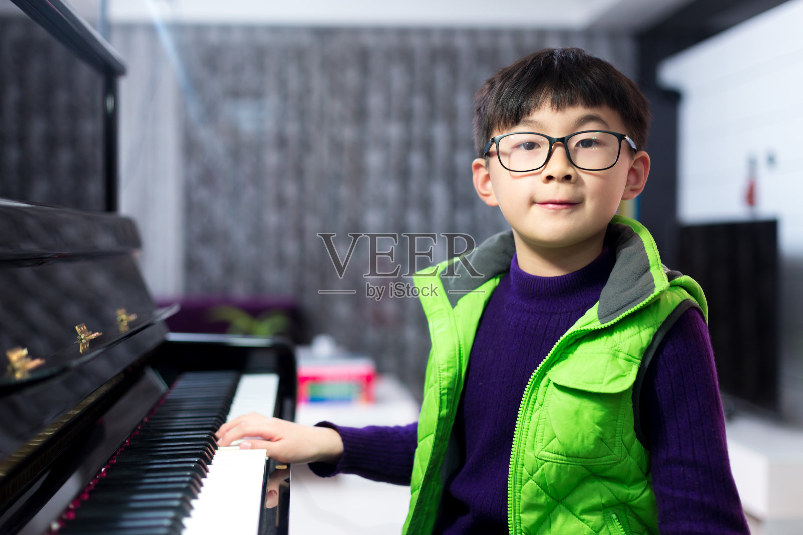 表情可爱的小男孩拿着银杯坐在钢琴旁照片摄影图片