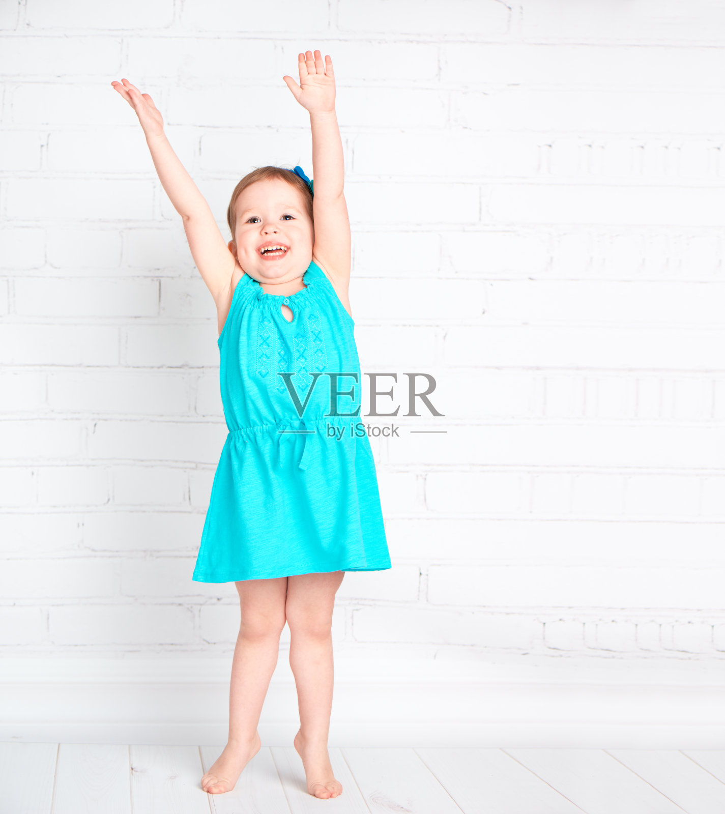 快乐的小女孩举起双手，量了量身高照片摄影图片