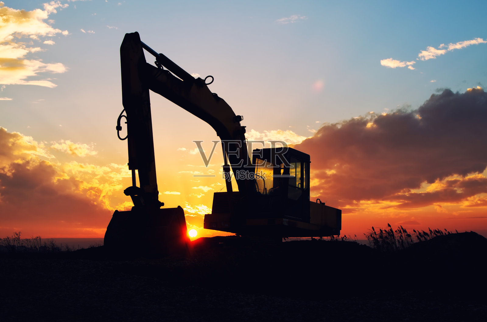 夕阳下的挖掘机剪影。照片摄影图片