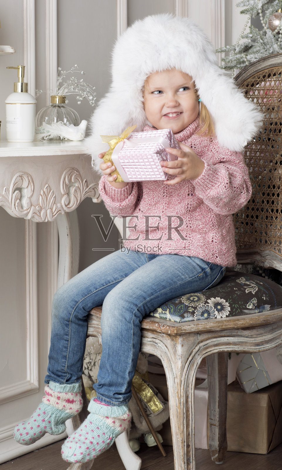 孩子坐在椅子上，拿着一份礼物。照片摄影图片