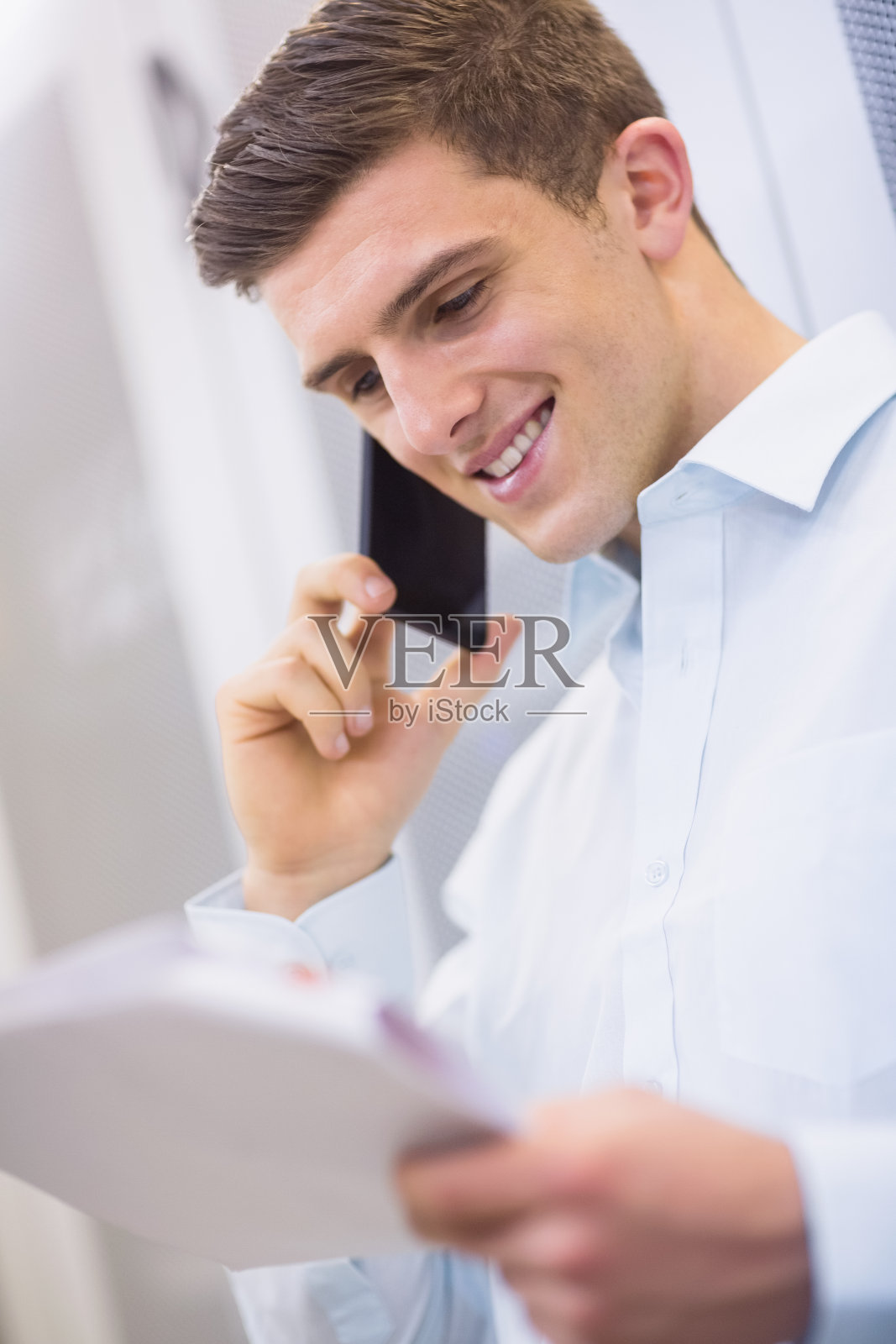 微笑的技术人员打电话并阅读一份文件照片摄影图片