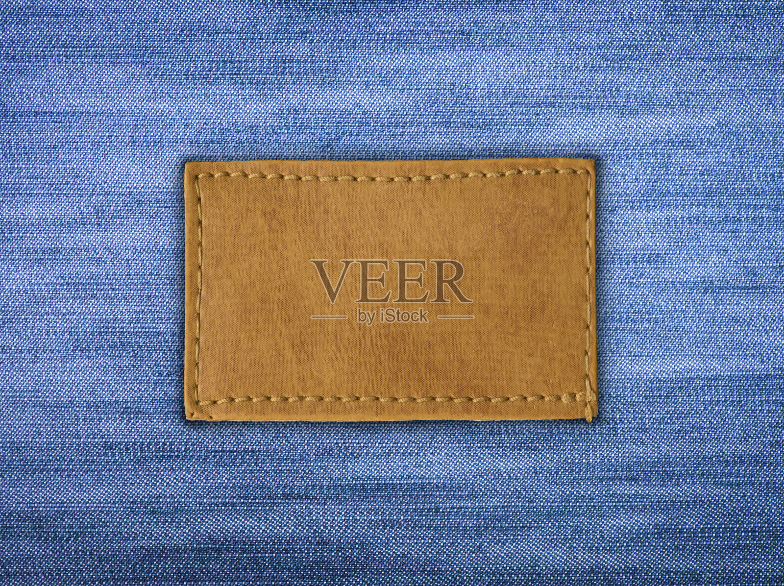 空白皮革牛仔裤标签缝在蓝色牛仔裤上照片摄影图片