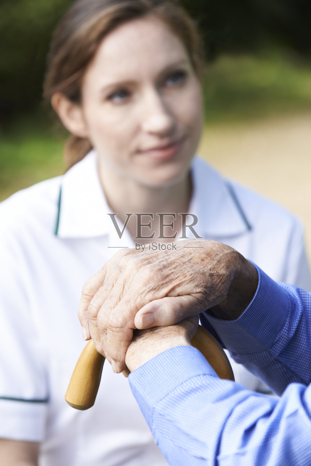 老人的手在拐杖上，护工在里面照片摄影图片