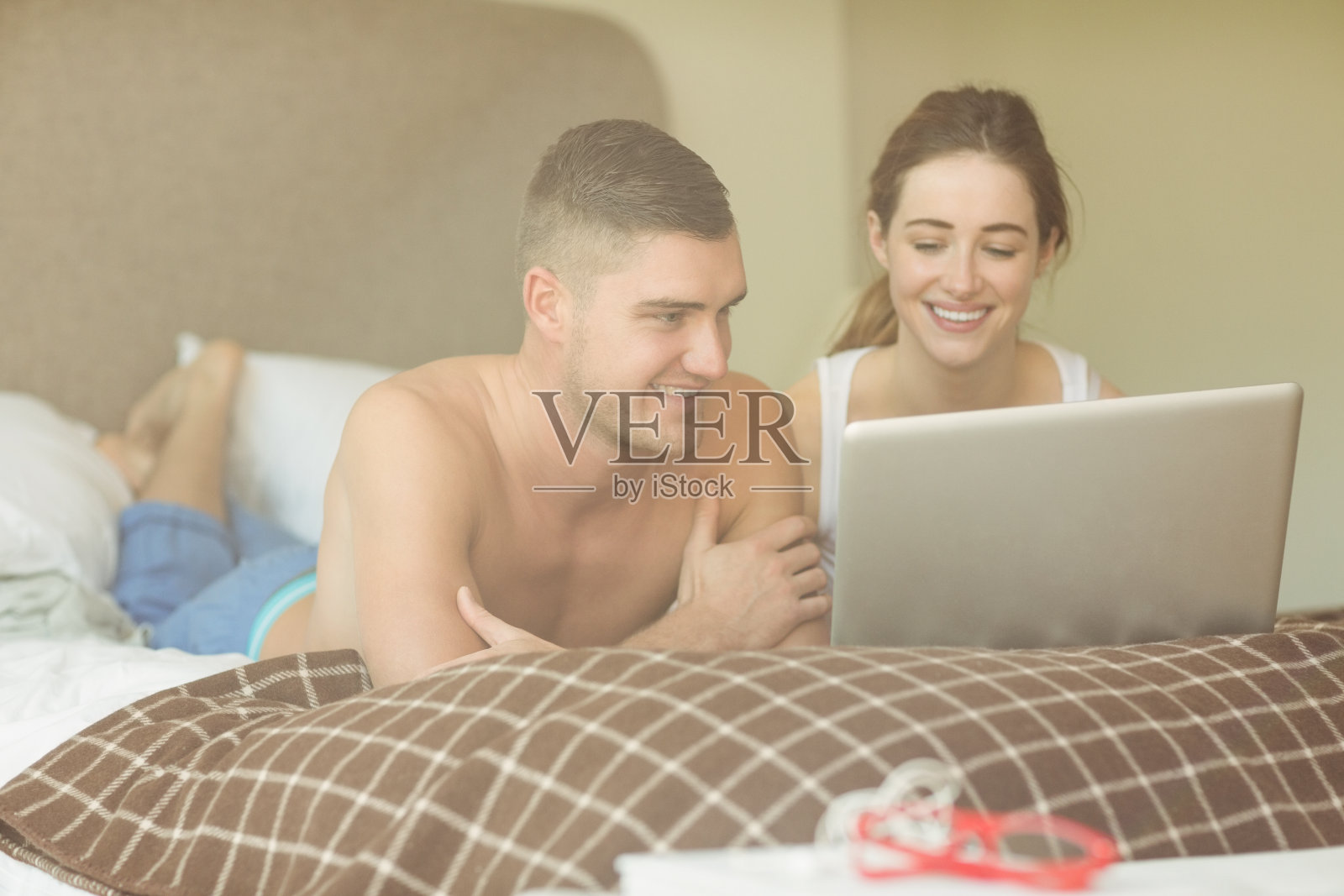 可爱的夫妇在床上使用笔记本电脑照片摄影图片