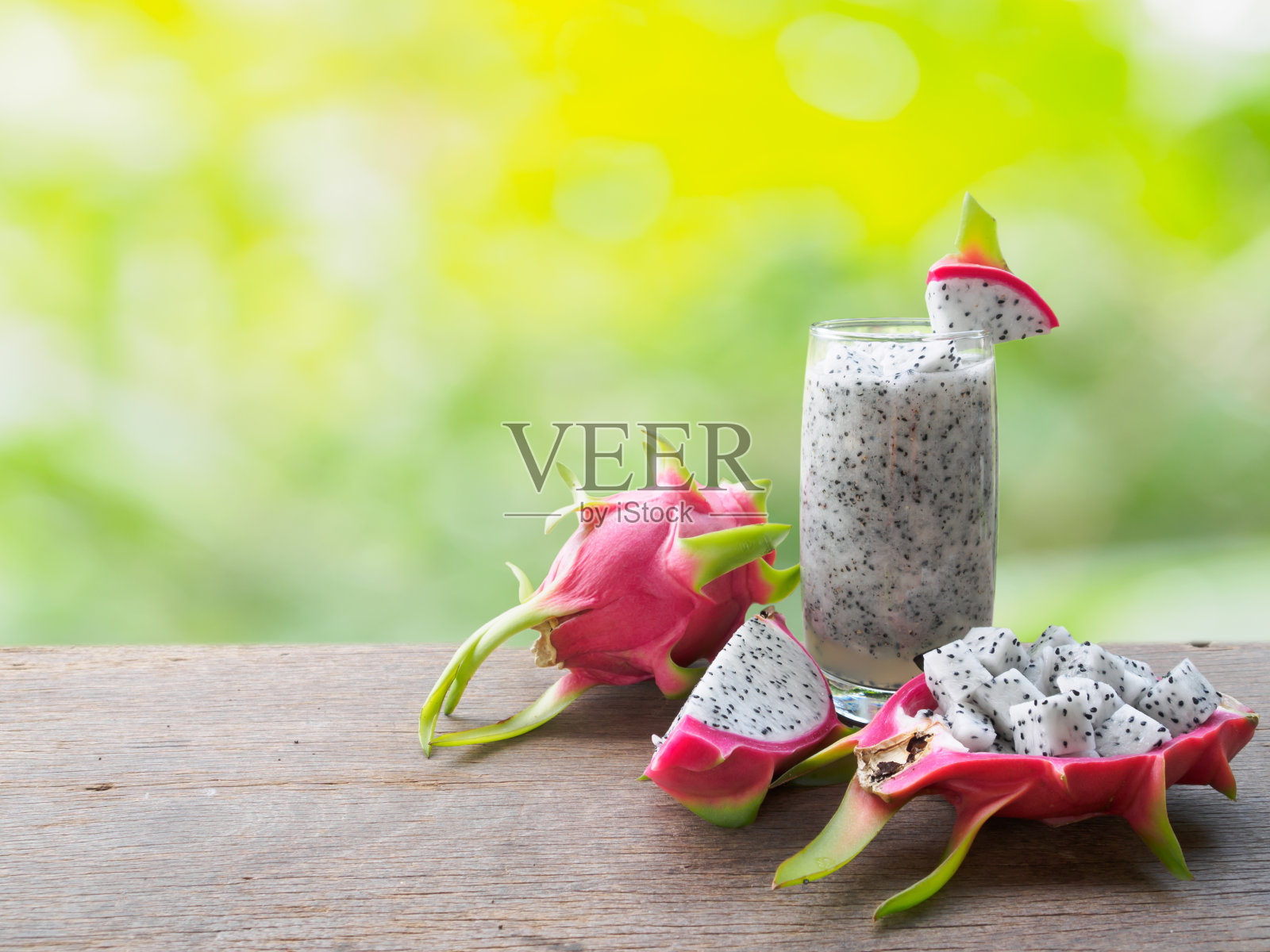 一杯冰沙火龙果和切片放在自然背景的木桌上照片摄影图片