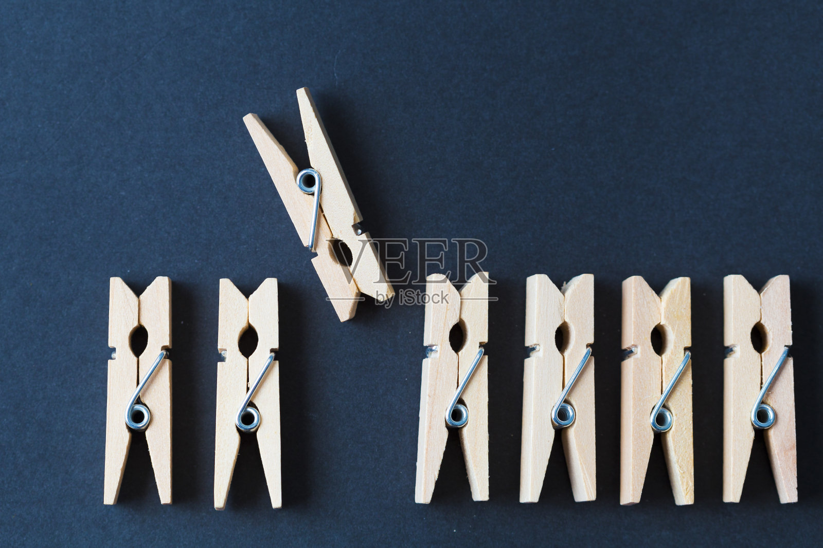 在深色背景上排成一排的木衣夹照片摄影图片