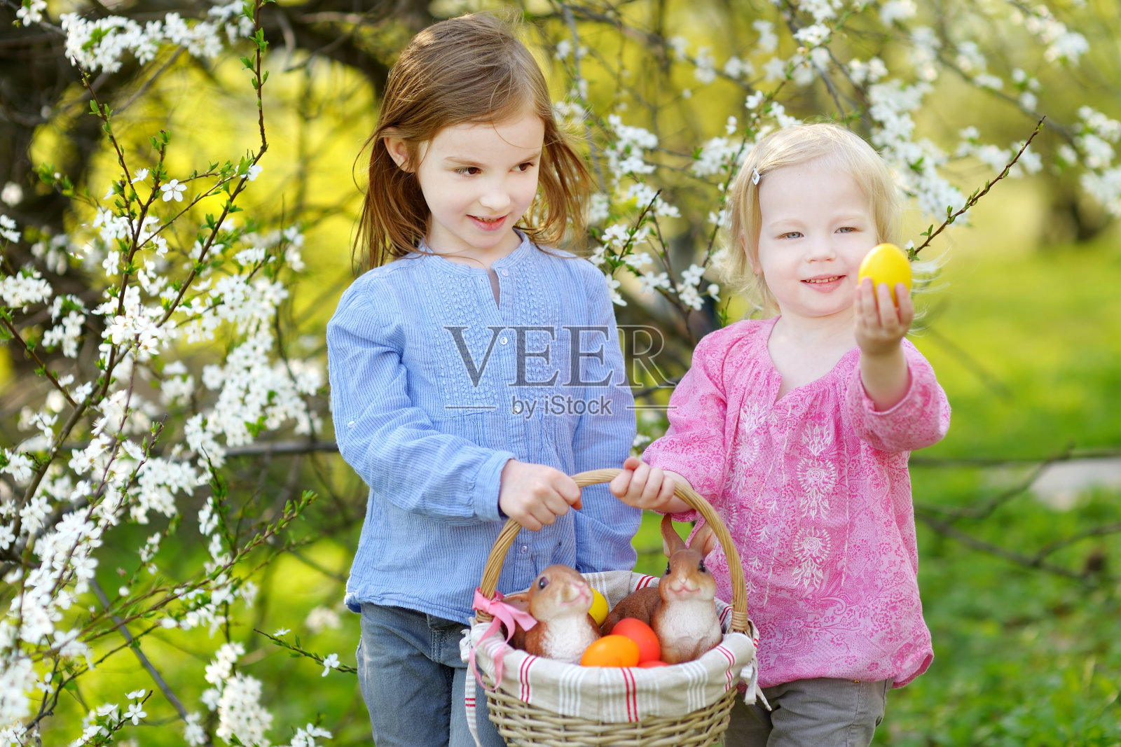 两个小女孩提着一篮子复活节彩蛋照片摄影图片