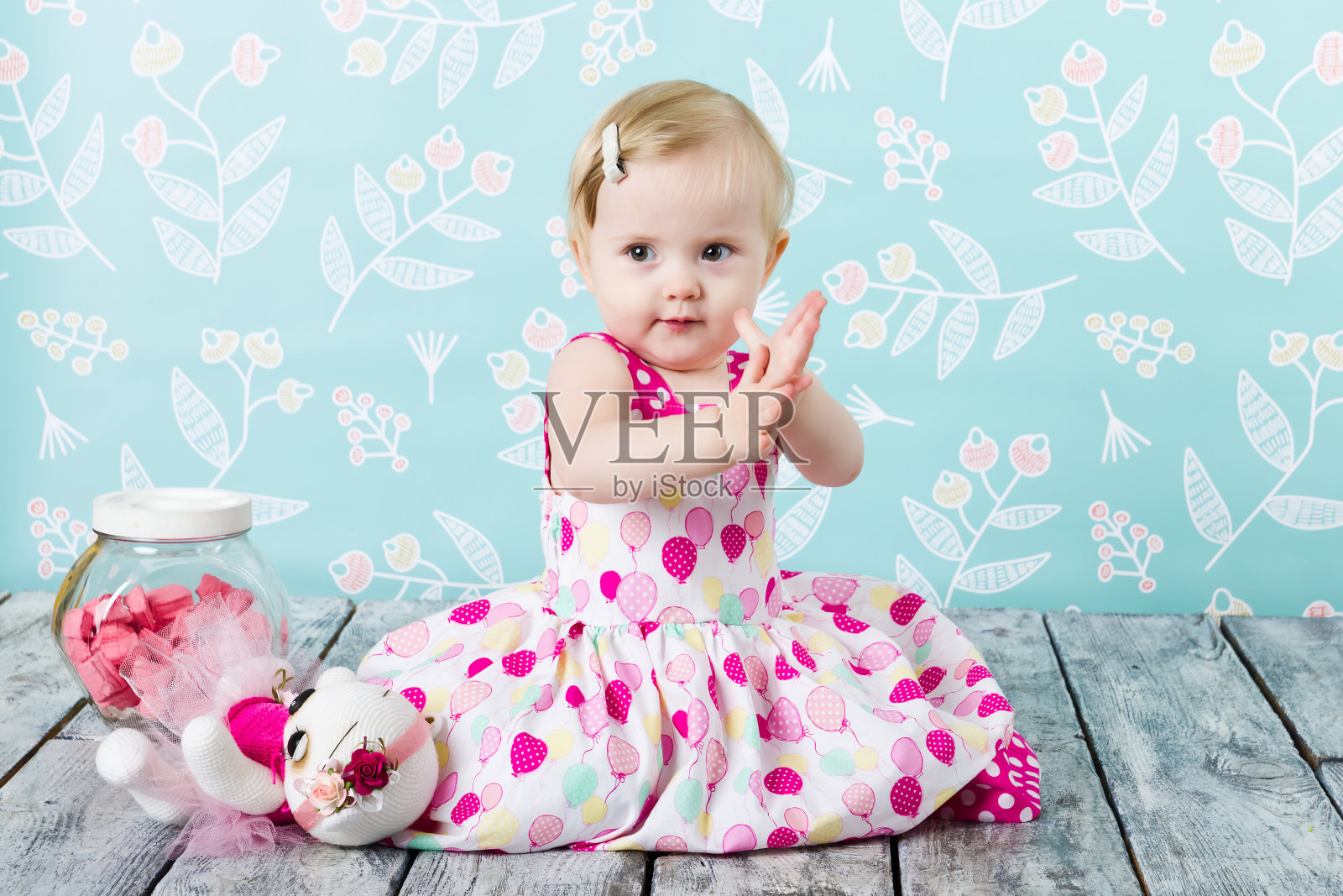 小女孩坐在木地板上，旁边放着糖果罐照片摄影图片