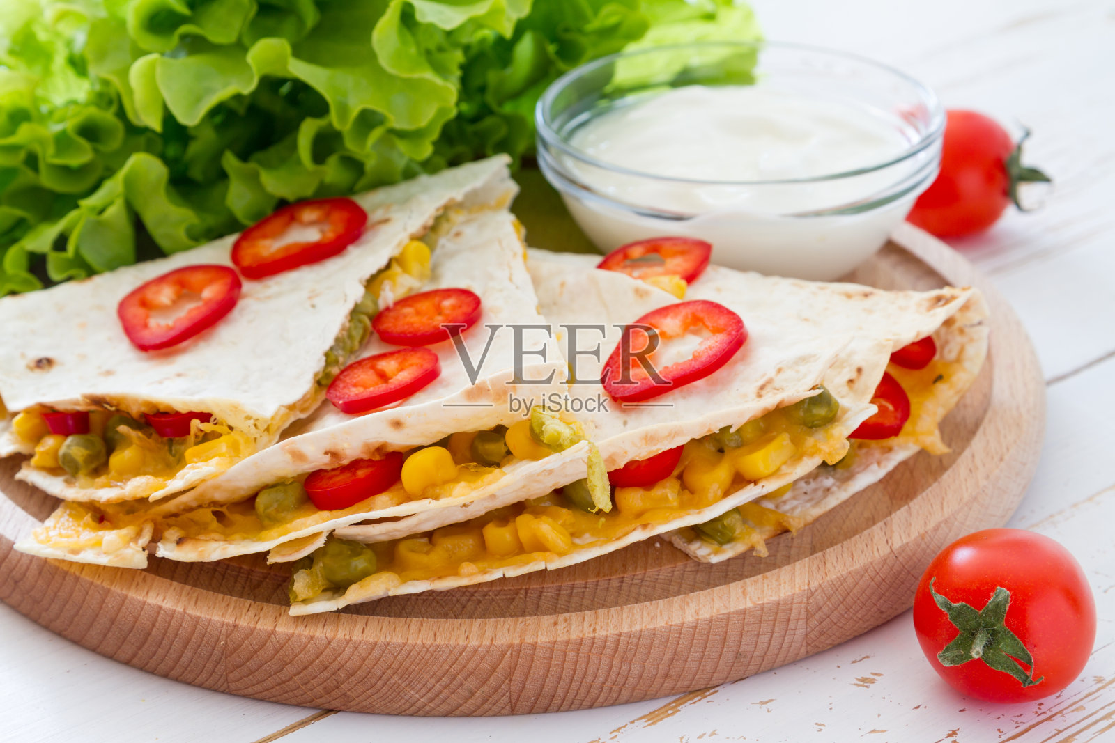 墨西哥玉米饼切片，配酸奶酱放在木板上照片摄影图片