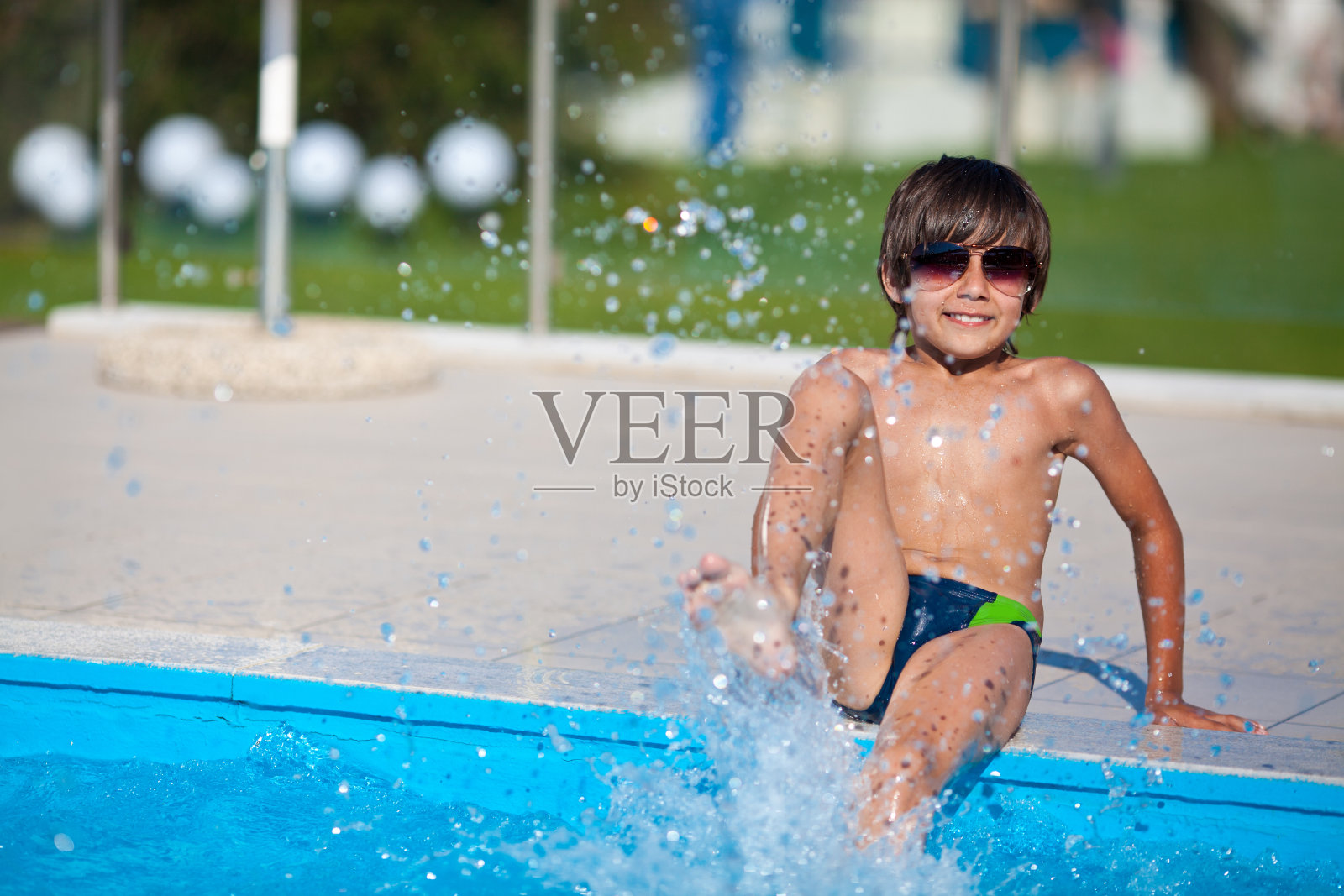 度假的男孩坐在泳池边照片摄影图片