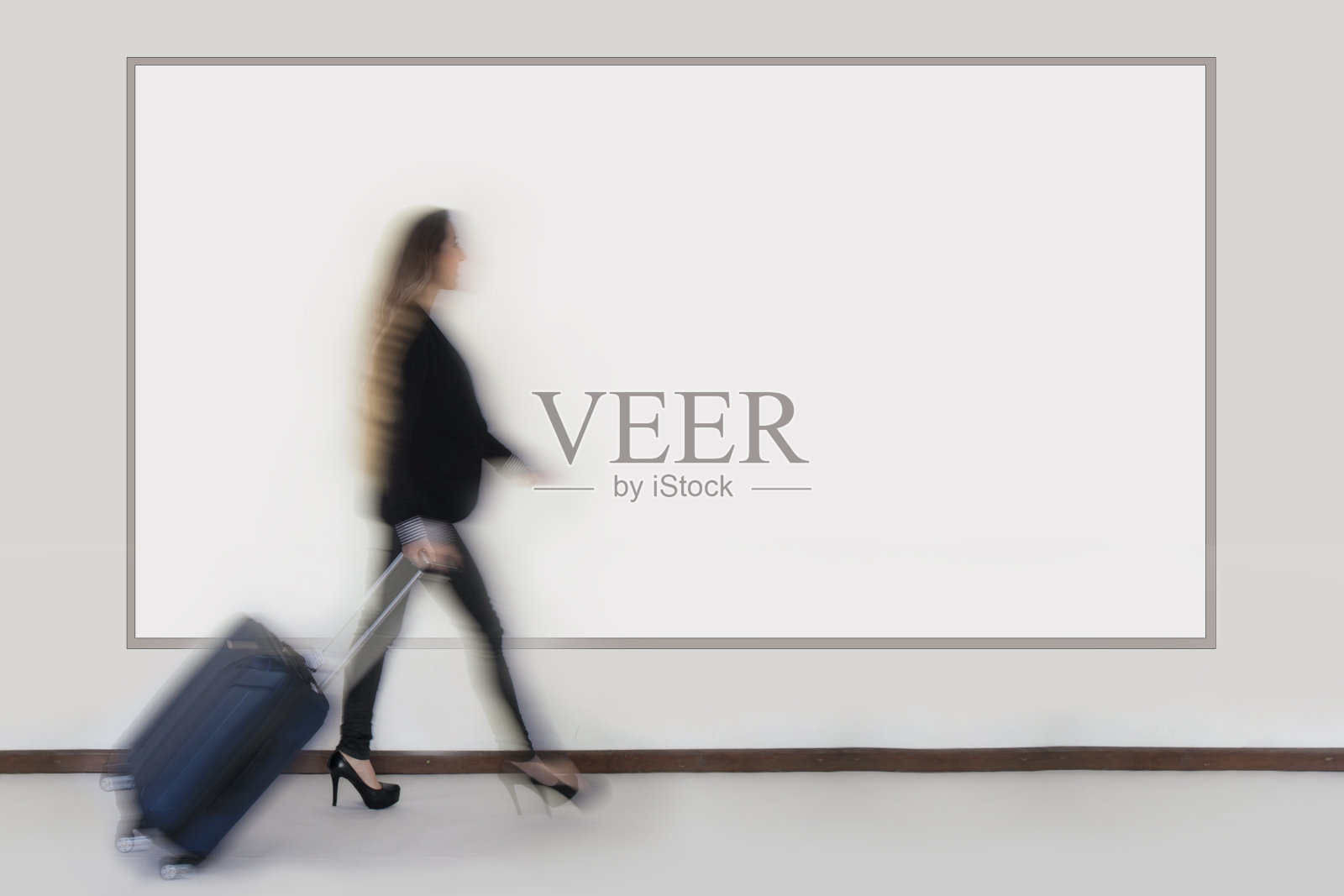 一个女人提着箱子在一个牌子前走过照片摄影图片