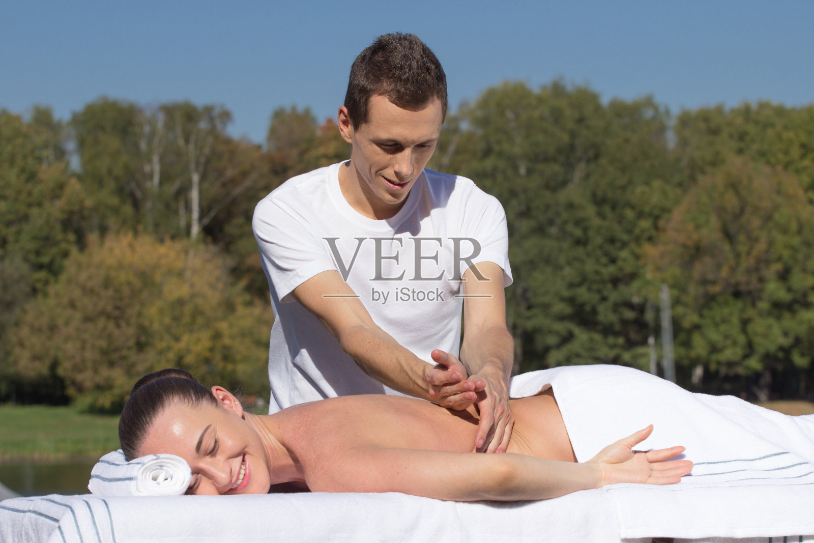 男人在户外给年轻的黑发女子按摩照片摄影图片