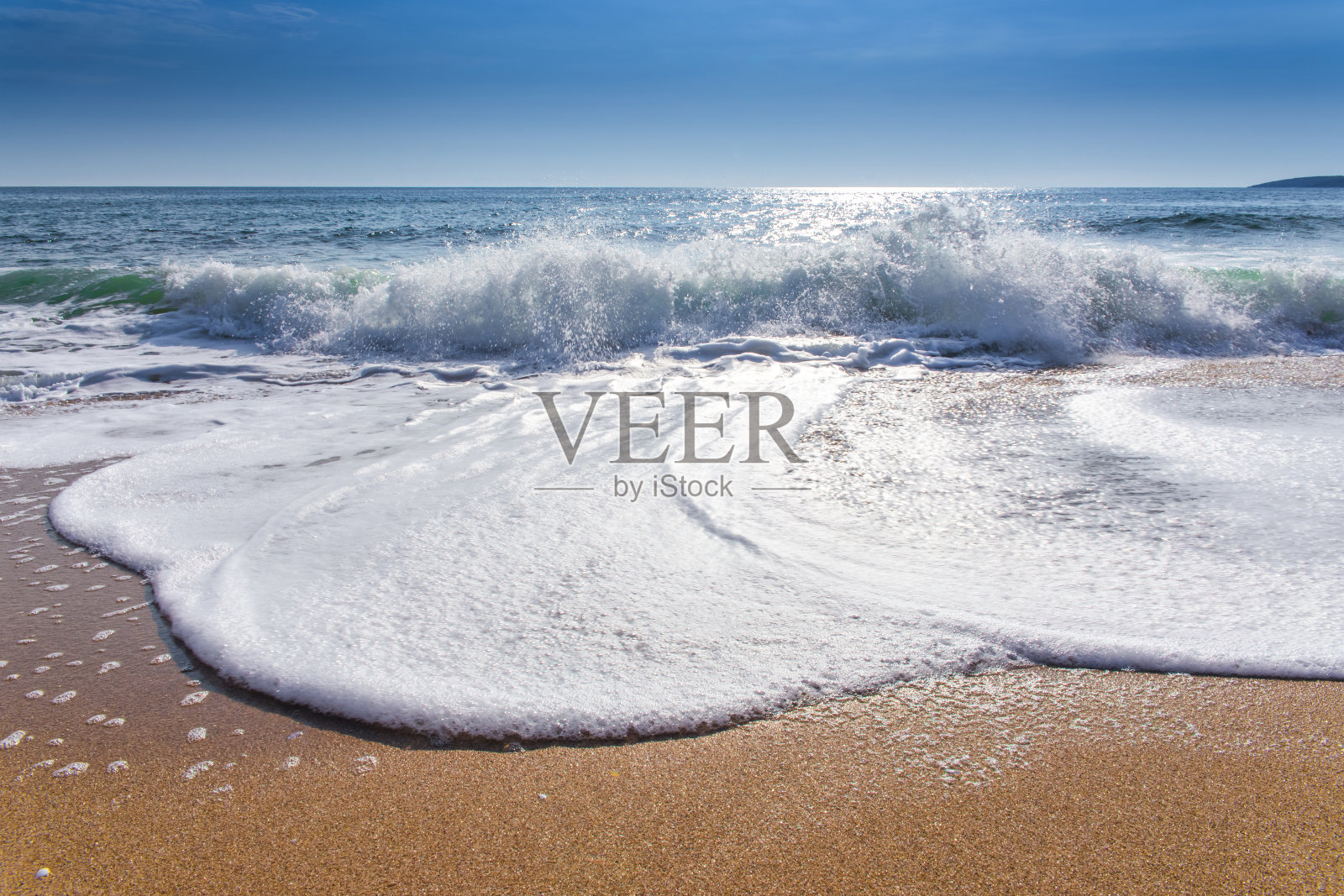 沙滩，蔚蓝的天空，日出和海水的飞溅照片摄影图片