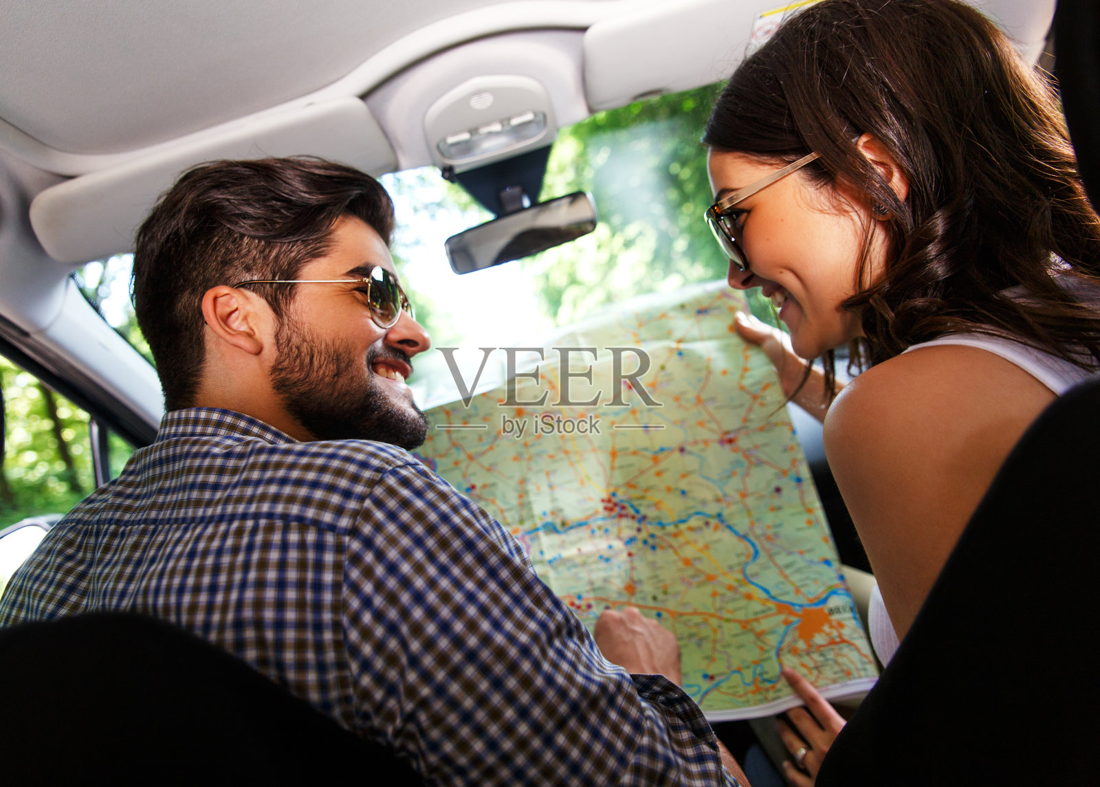 一对幸福的年轻夫妇，车里有地图。照片摄影图片