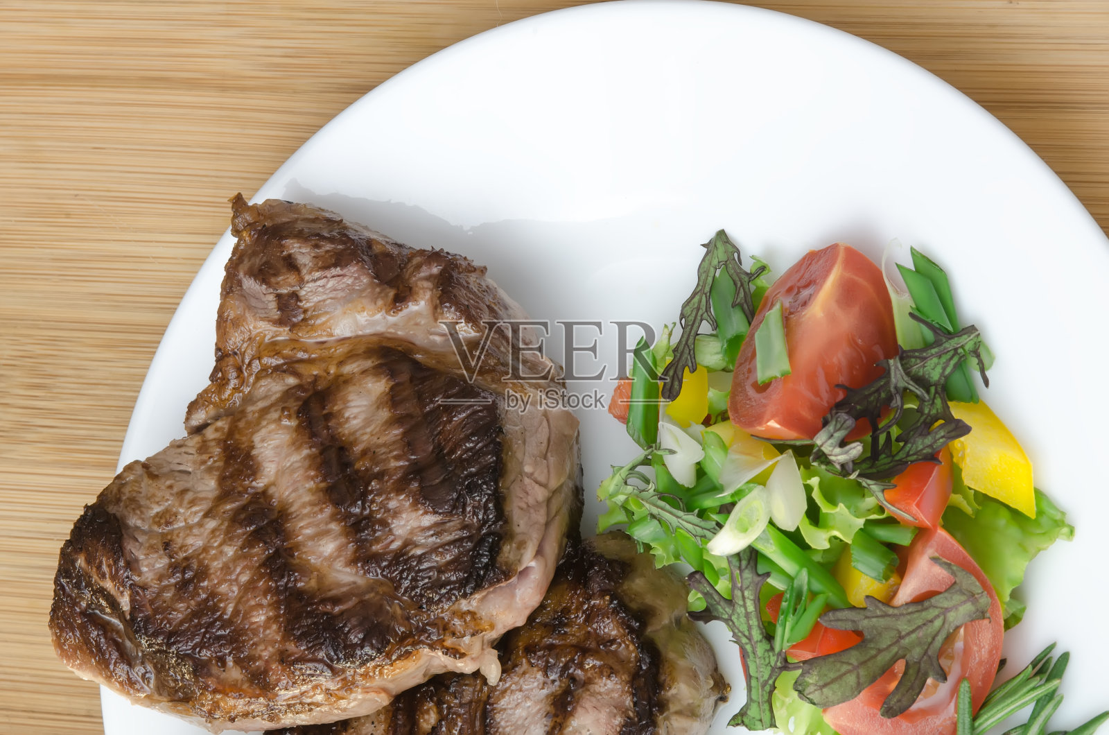 木背景的白盘上烤肉和沙拉照片摄影图片