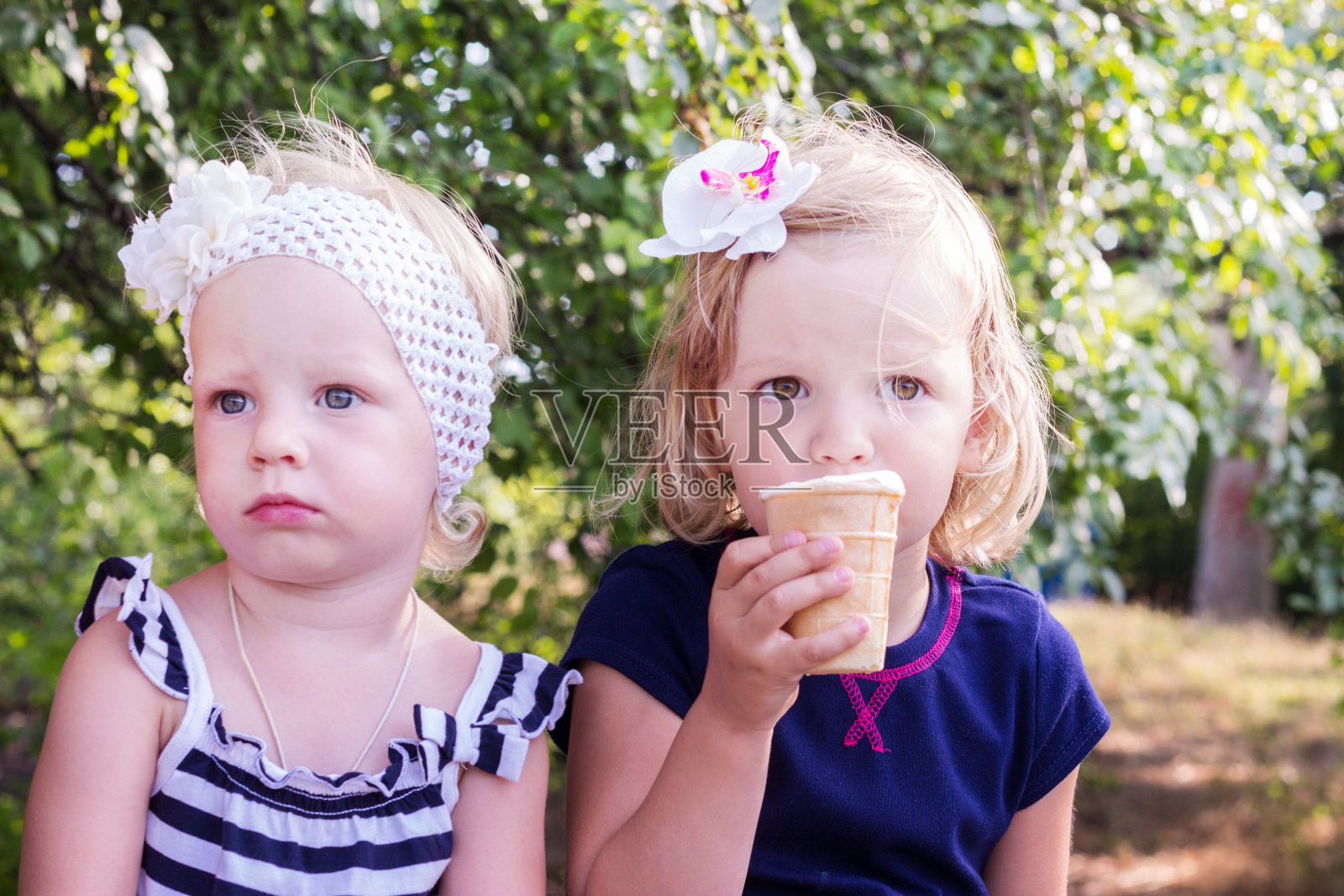 漂亮的小女孩(姐妹)在吃冰淇淋。照片摄影图片