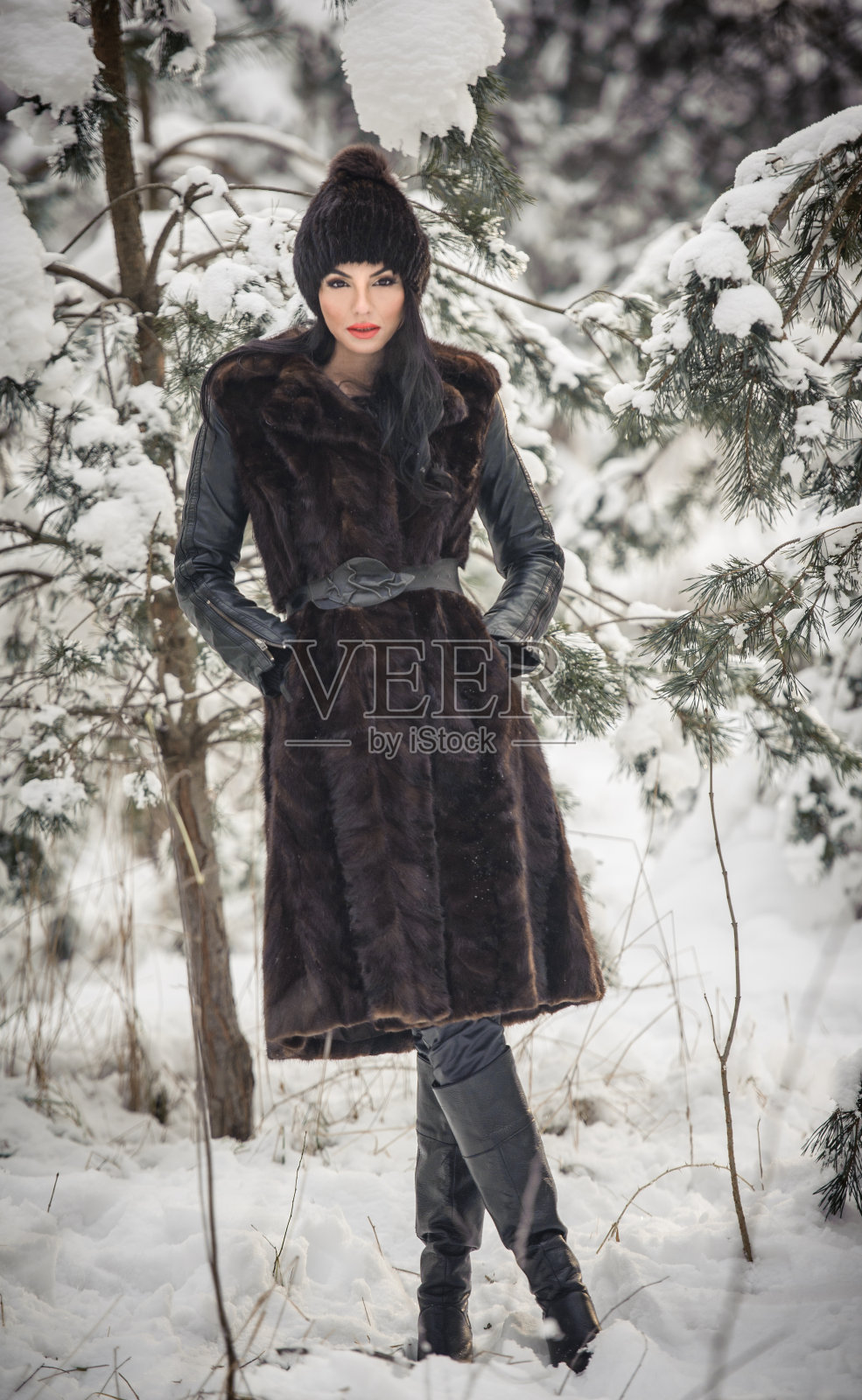 黑发女孩在白雪覆盖的树下摆姿势照片摄影图片
