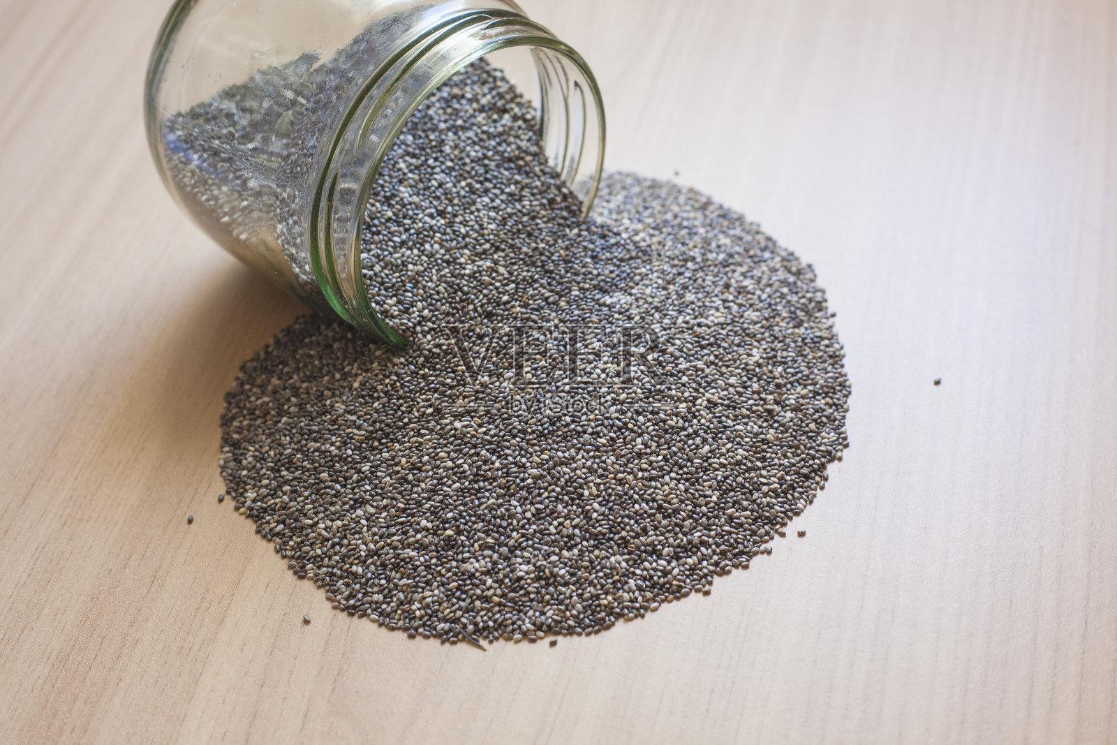 玻璃罐与奇亚种子洒在木制表面照片摄影图片
