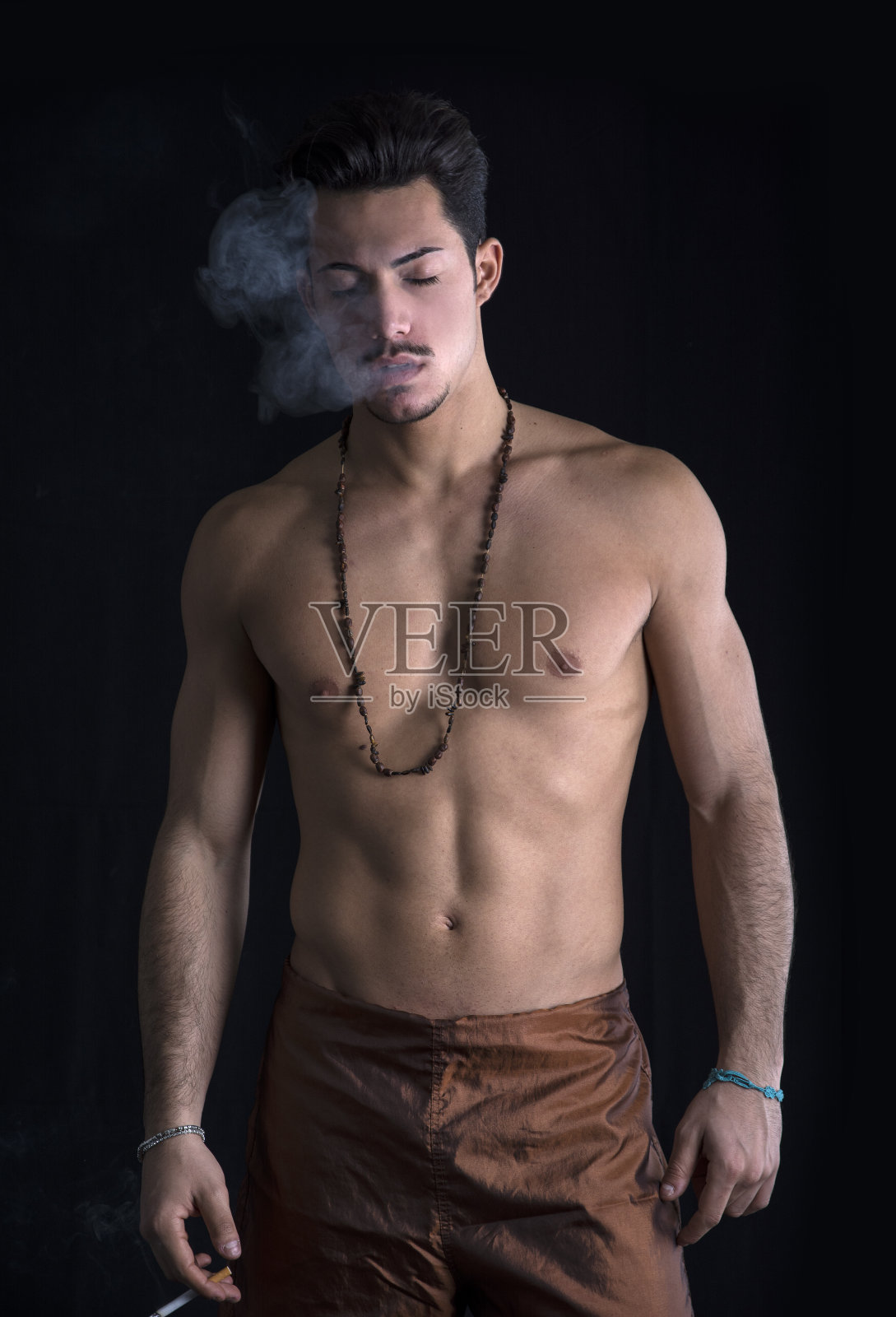 运动赤膊，留着胡子，抽烟的年轻人照片摄影图片