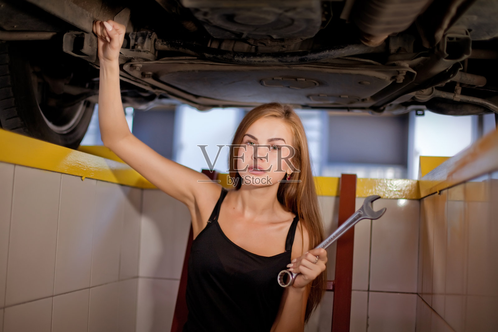 年轻性感的褐发机修工穿着格子衬衫在车库里。照片摄影图片