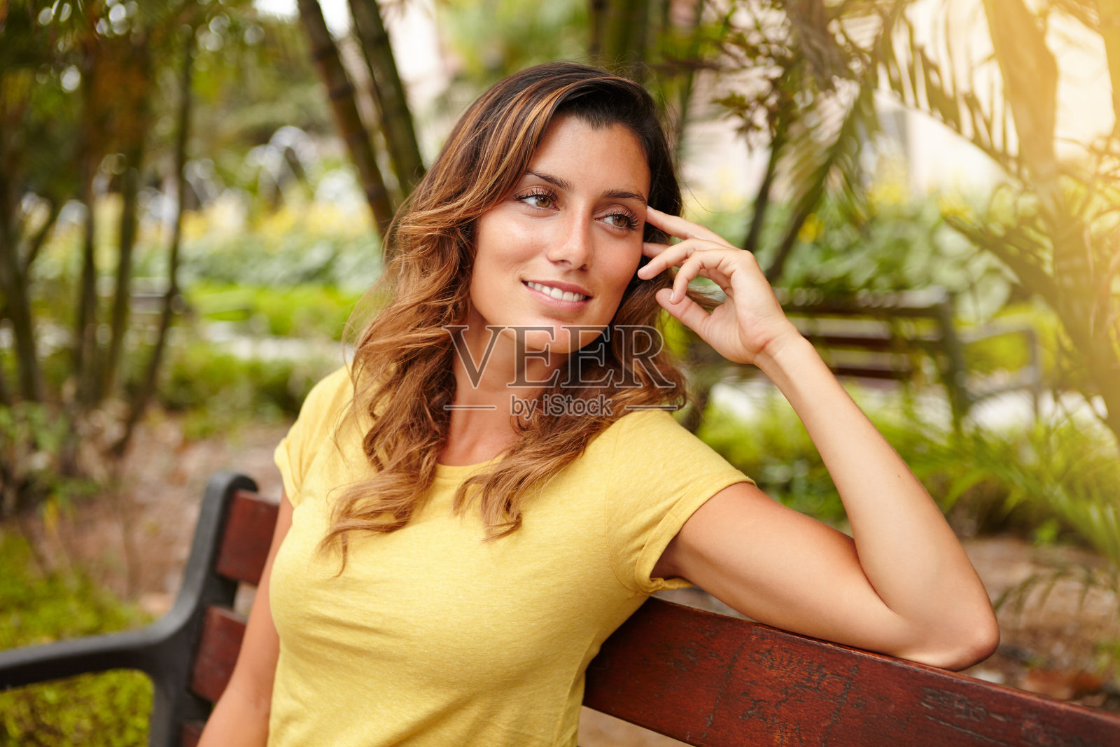 微笑的女士坐在长椅上，手插着头发照片摄影图片