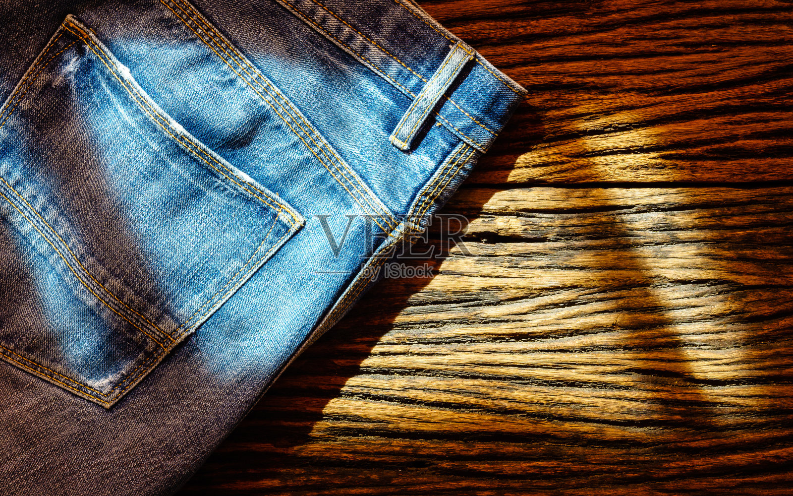木制背景上的蓝色牛仔裤，顶视图与复制空间照片摄影图片