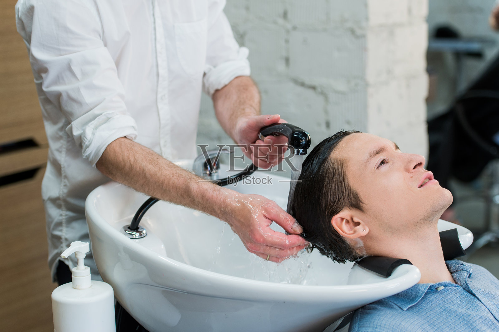 发型师:理发师在为顾客洗头——年轻人在里面放松照片摄影图片