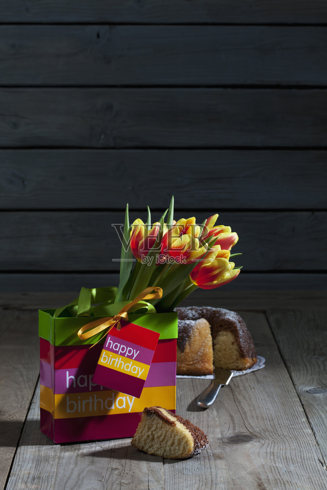 郁金香装在礼品袋里，大理石蛋糕放在木头上照片摄影图片