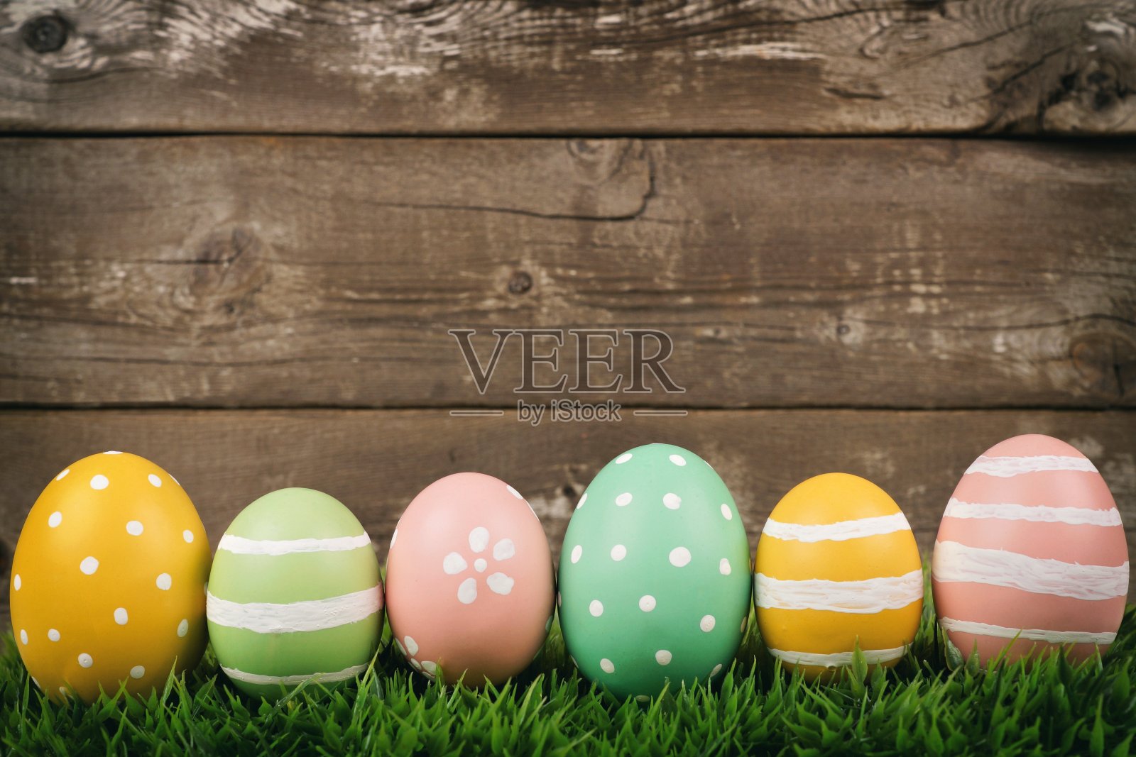 在粗糙的木头上的草地上，一排排的复活节彩蛋照片摄影图片