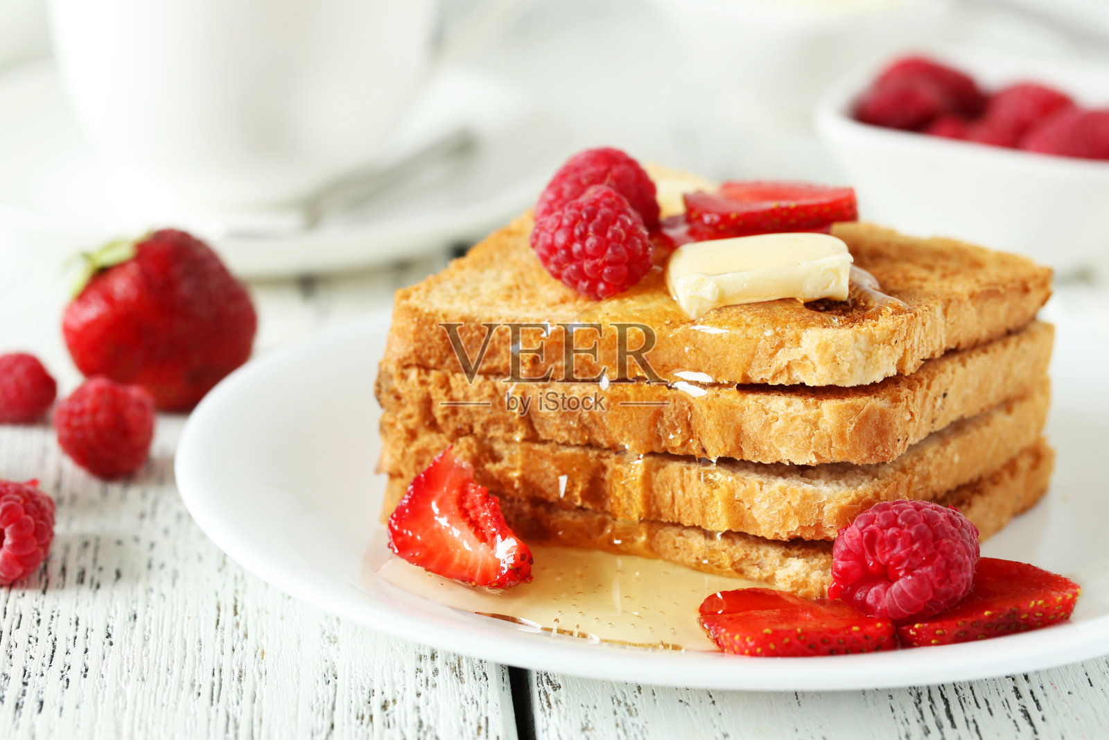 新鲜的烤面包配上覆盆子和草莓，放在白色的木背架上照片摄影图片