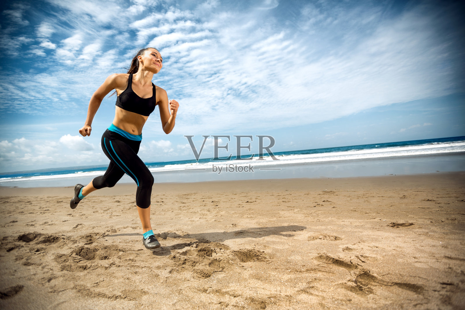 在海边沙滩上跑步的运动女人照片摄影图片