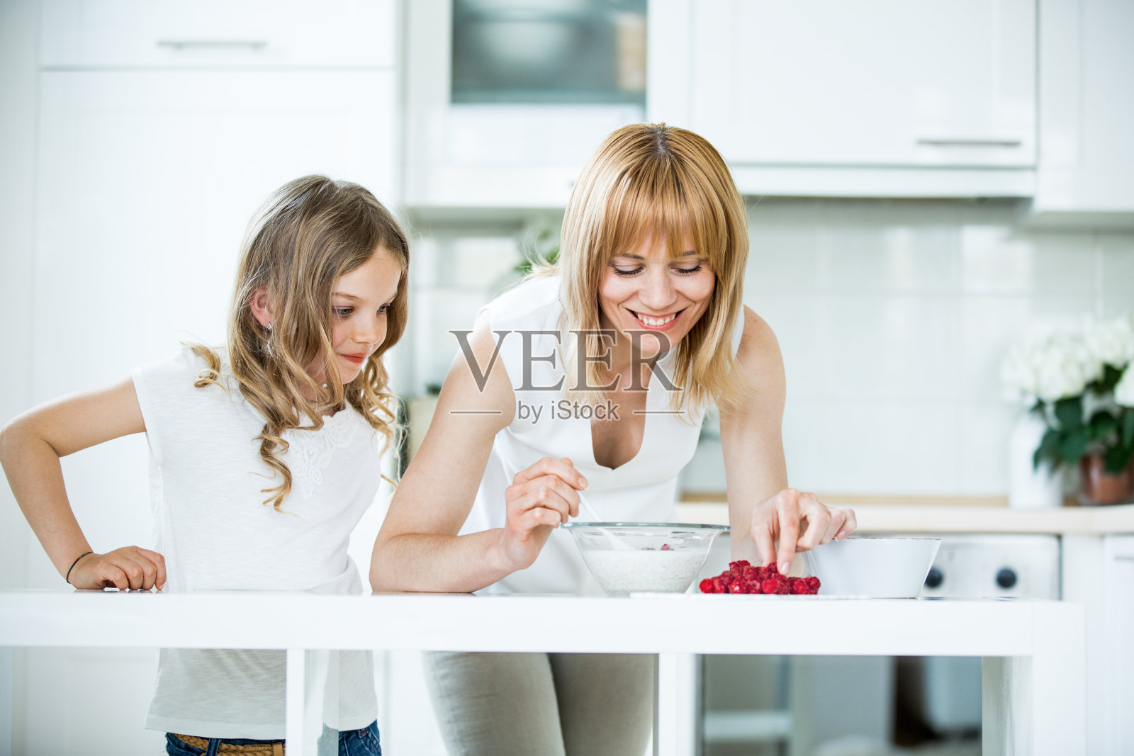 母亲和女儿准备用覆盆子做早餐照片摄影图片